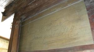 Signed and dated 1904 in beautiful cursive -- likely when the panel was put back in to cover the earlier hole made when a stove was installed