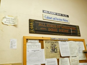 "Don't feed the woodworkers" and "All Kinds of Woodwork Done Here" signs by the entrance to Cabinet and Furniture Making department at NBSS.